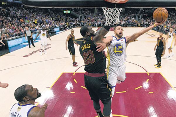 Curry lanza ante la oposición de James, mientras Durant espera el desenlace de la jugada.