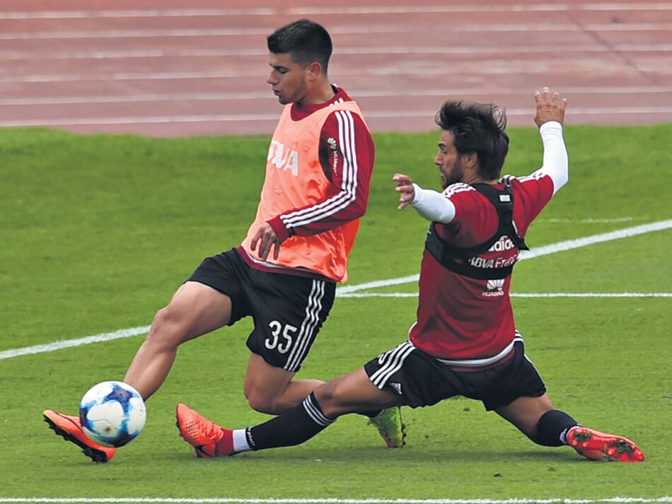 Luciano Lollo intenta llevarse la pelota ante la marca de Ponzio, quien será titular hoy.