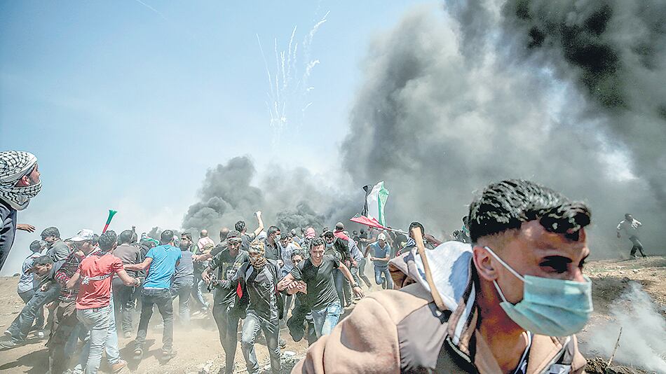 Manifestantes corren para protegerse del gas lacrimógeno anteayer en la frontera entre Israel y la Franja de Gaza.