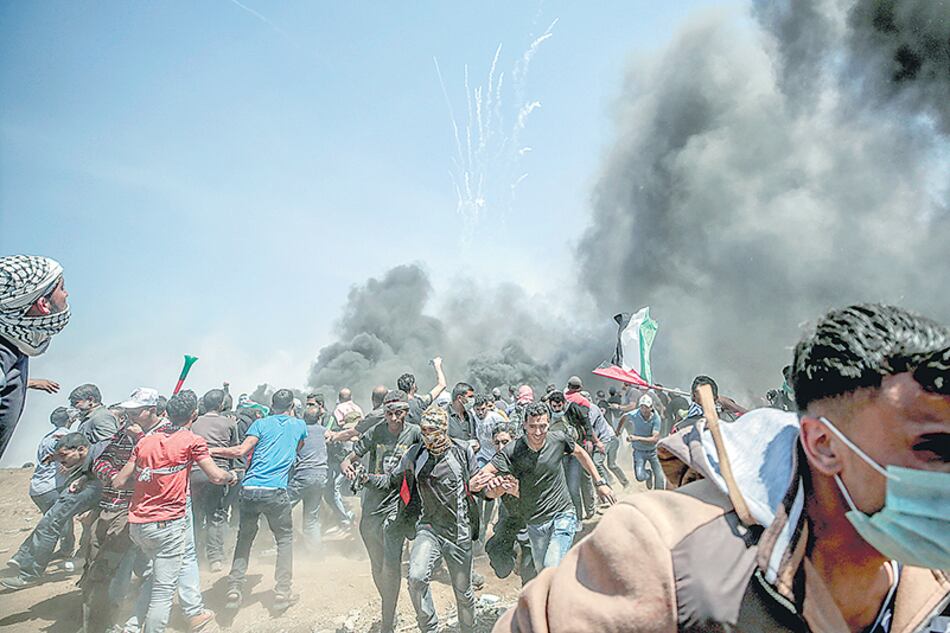 Manifestantes corren para protegerse del gas lacrimógeno anteayer en la frontera entre Israel y la Franja de Gaza.