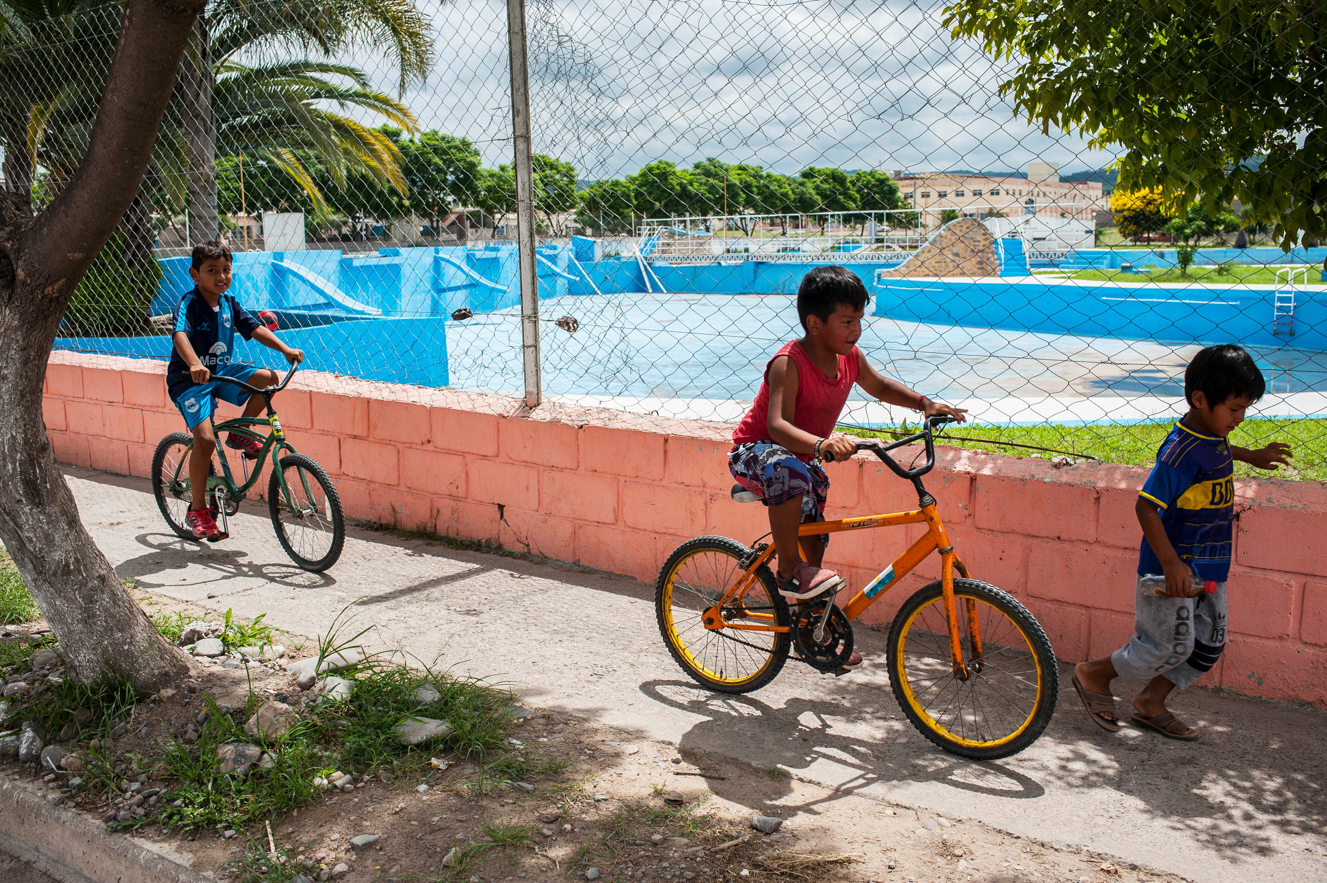Las piletas vacías obligan a los chicos a entretenerse en bicicleta en pleno verano