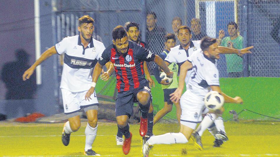 Gudiño intenta avanzar, cercado por hombres de Gimnasia.