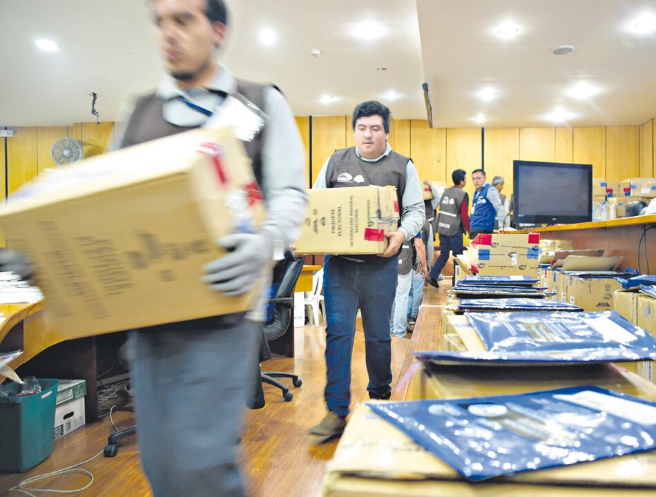 Miembros del Consejo Nacional Electoral cargan cajas con votos durante el conteo en Quito.