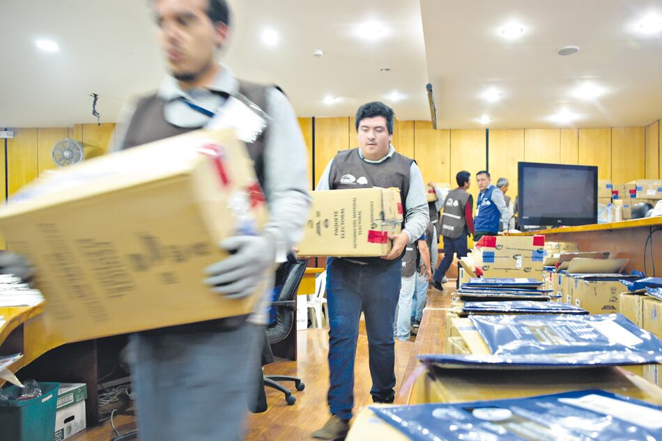 Miembros del Consejo Nacional Electoral cargan cajas con votos durante el conteo en Quito.