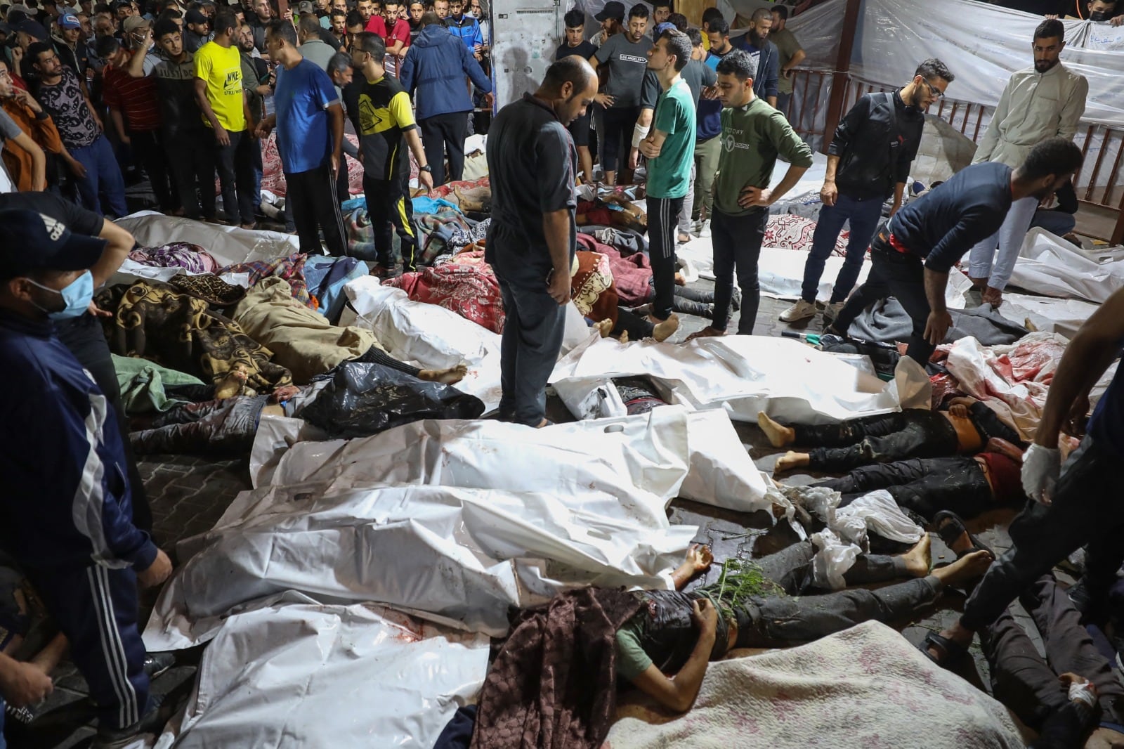 Palestinos rodean cadáveres de lasvíctimas delbombardeo al hospital.