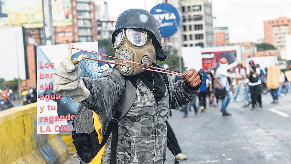 Un activista opositor usa una gomera durante una protesta contra el gobierno de Maduro.