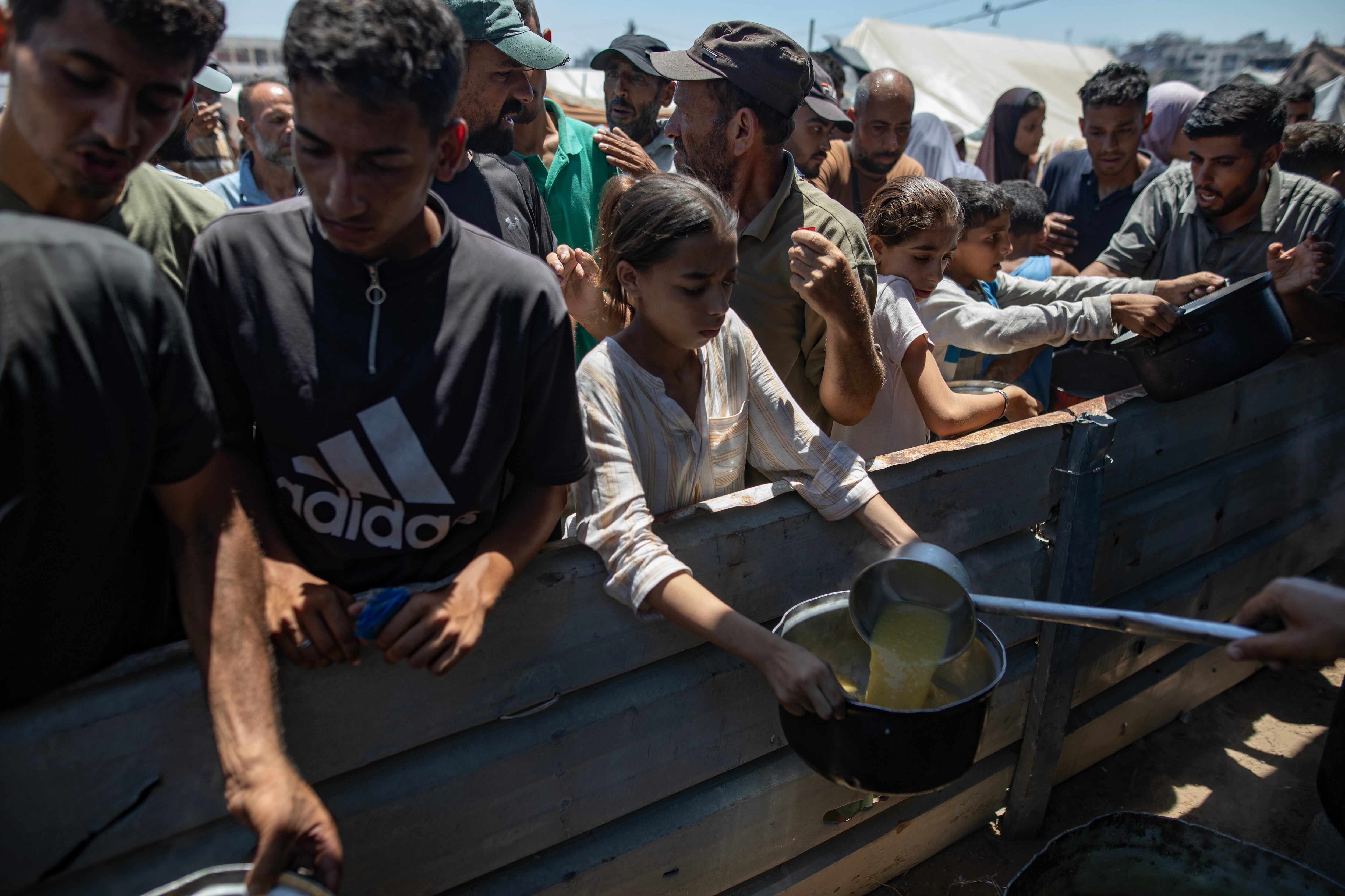 Gazatíes reciben alimentos en un centro de reparto.