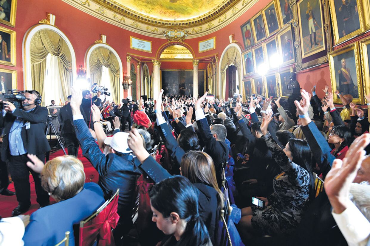 Miembros de la Asamblea Nacional Constituyente levantan sus manos durante su instalación en el Congreso venezolano.