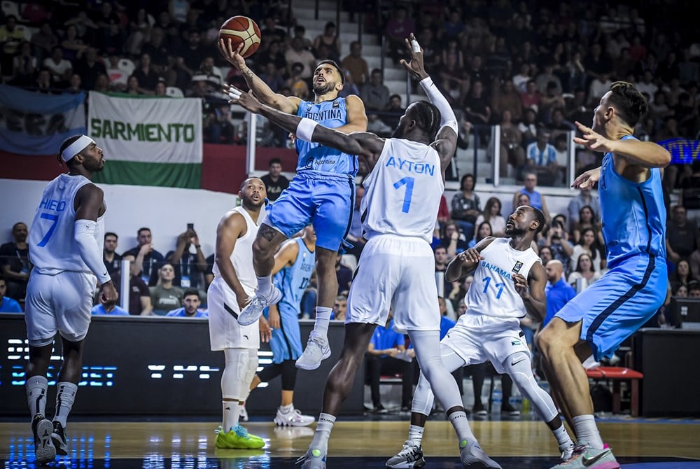 Campazzo encara ante la marca del NBA DeAndre Ayton. El gigante de Bahamas fue determinante
