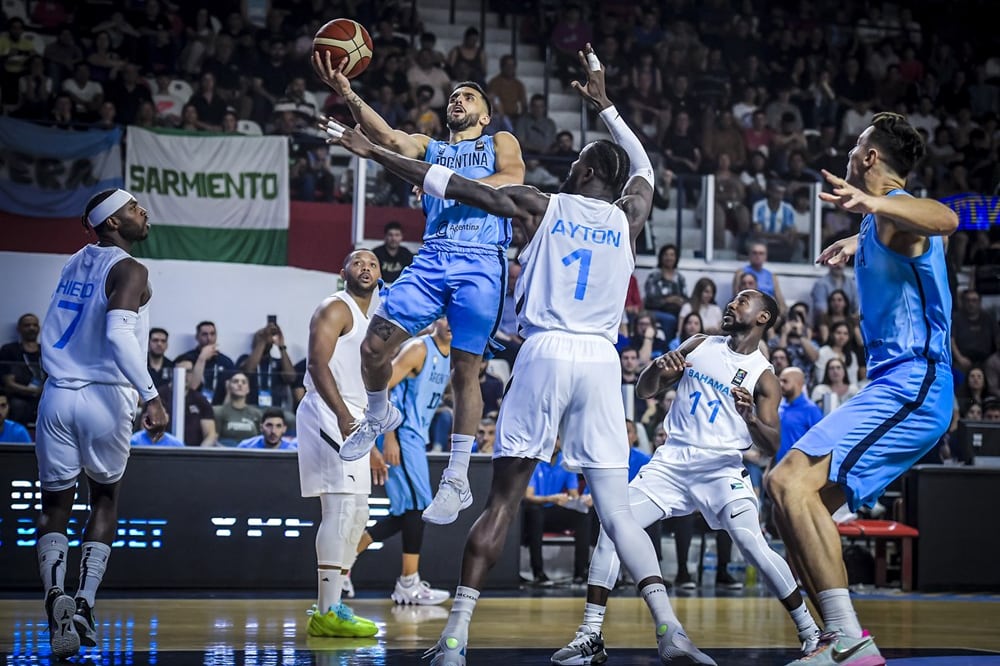 Campazzo encara ante la marca del NBA DeAndre Ayton. El gigante de Bahamas fue determinante