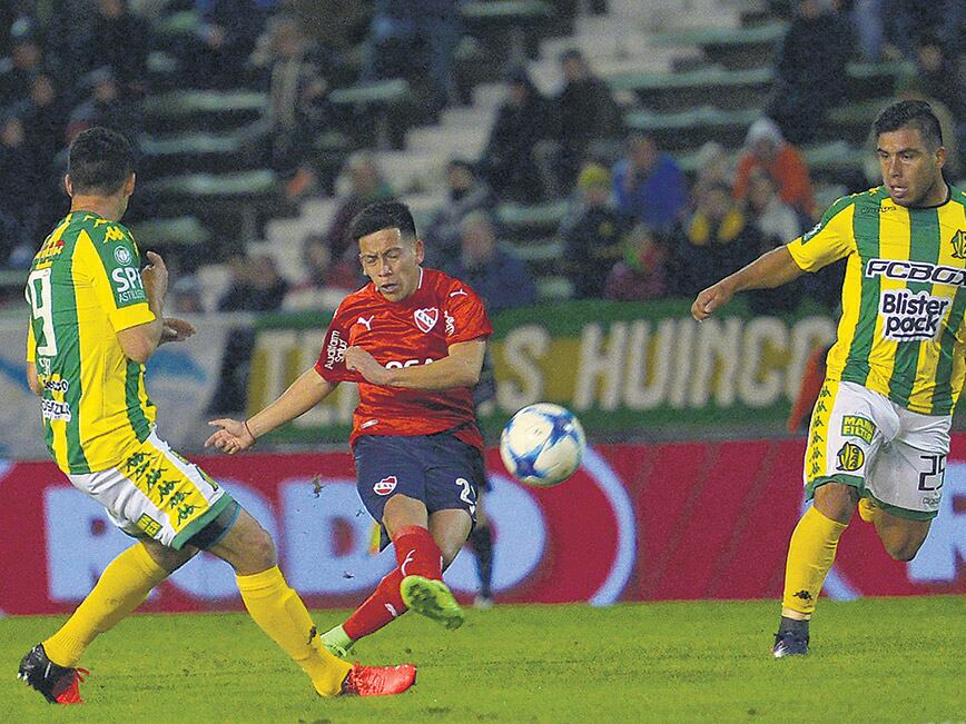 El chico Barco remata ante la presencia de dos jugadores marplatenses.