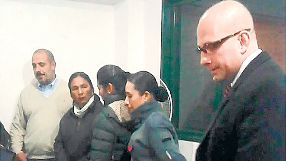 Entre el secretario Horacio García y dos penitenciarias, Milagro mira desafiante a su captor Pullen LLermanos, que baja la vista.