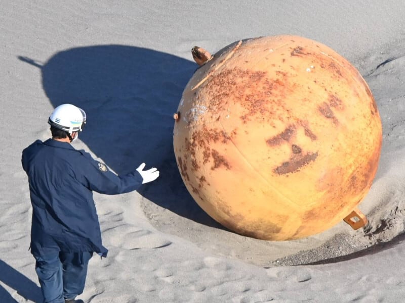 Dos agentes del escuadrón antibombas analizaron la esfera de metal encontrada en la playa japonesa de Enshuhama. (Foto: @lauraparquokka)