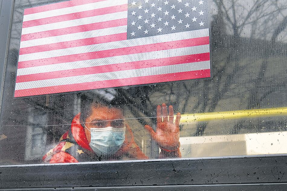 Un hombre saluda desde un micro en Queens, distrito de Nueva York, epicentro del coronavirus.