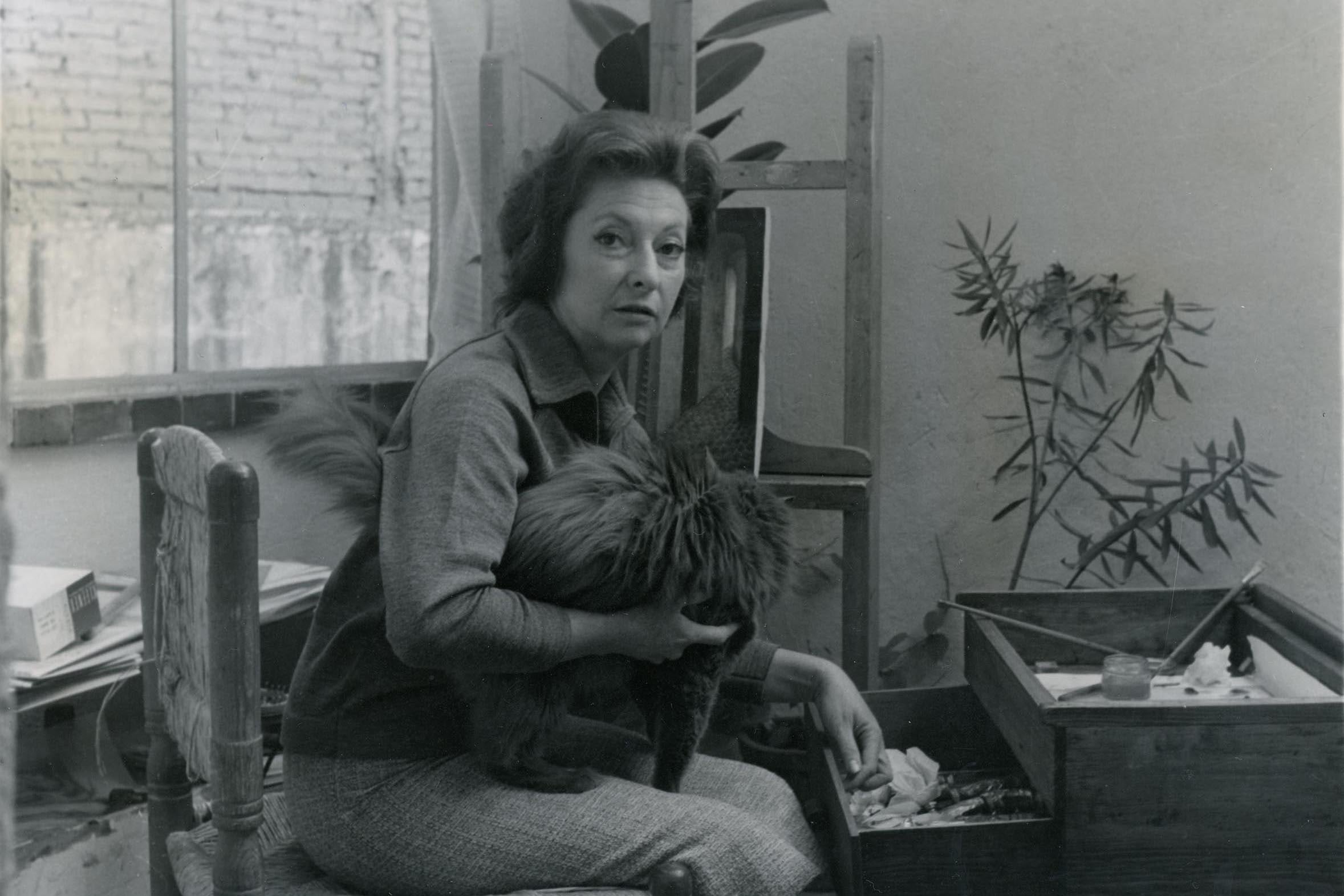 Remedios Varo en su estuidio con su gato Pituso y en el fondo el óleo Despedida. ca. 1957-58, por Kati Horna