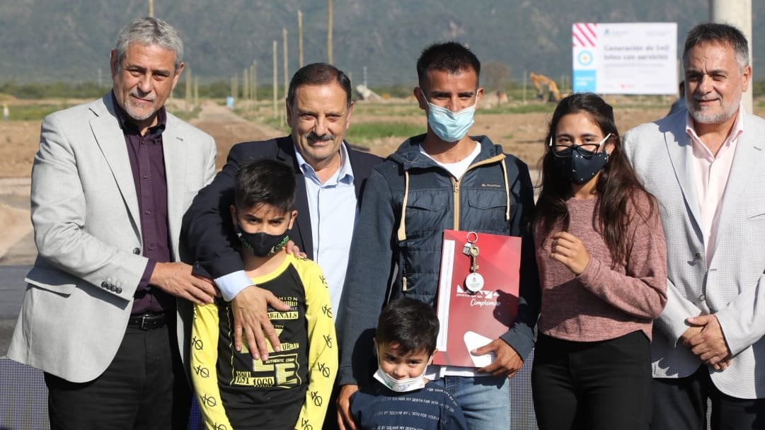 Jorge Ferraresi y Ricardo Quintela con una familia beneficiaria
