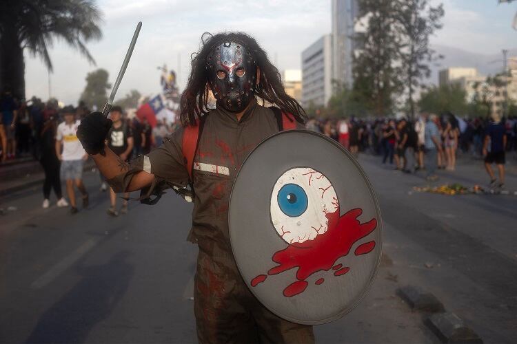 Un manifestante carga un escudo con un ojo sangrando, en una nueva marcha este viernes en Chile.