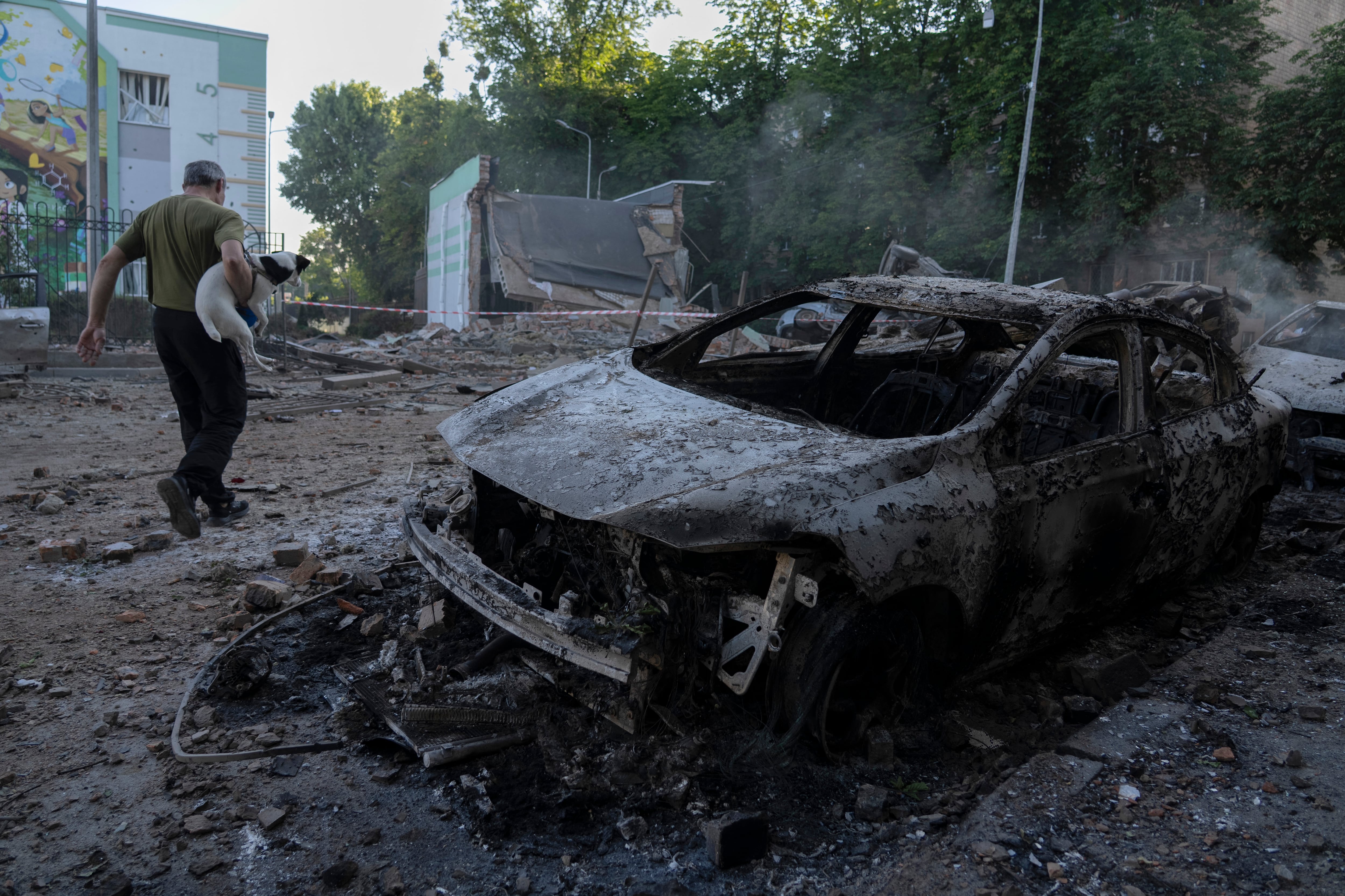 Un hmbre camina junto a un auto incinerado en un bombardeo ruso en Kiev.