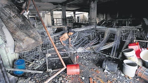 Un joven camina entre los escombros de la casa incendiada en el barrio Carlos Marx de Managua.