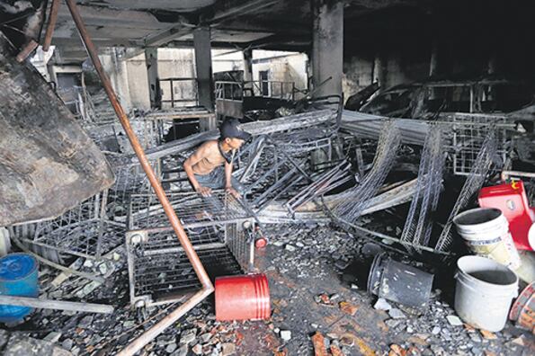 Un joven camina entre los escombros de la casa incendiada en el barrio Carlos Marx de Managua.