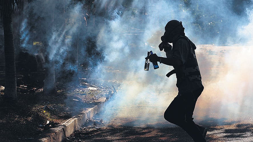 Un manifestante corre entre el gas lacrimógeno durante una marcha en Barquisimeto.