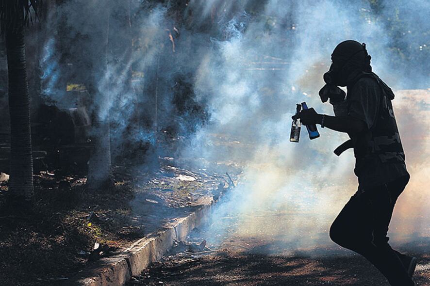 Un manifestante corre entre el gas lacrimógeno durante una marcha en Barquisimeto.