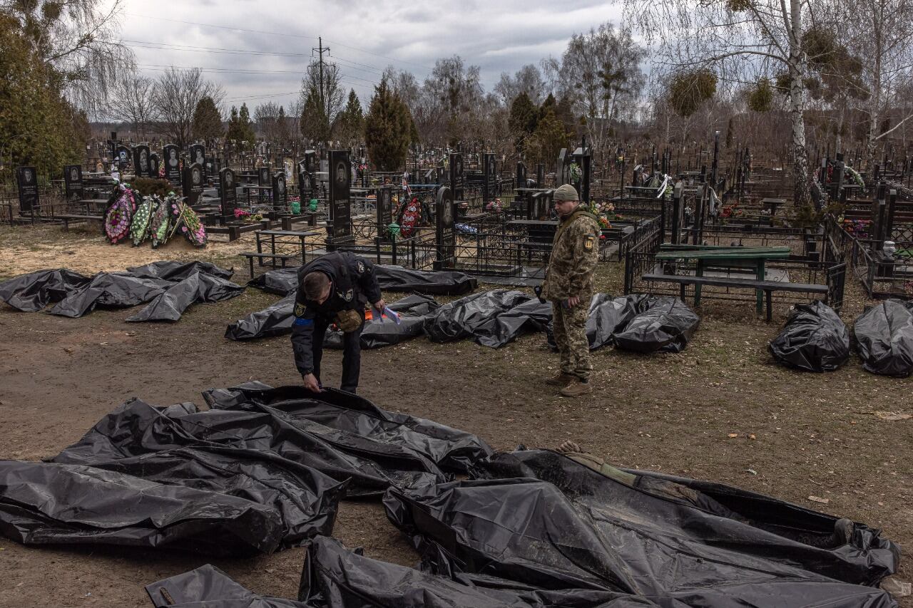 Dos policías observan los cadáveres trasladados al cementerio de Bucha.