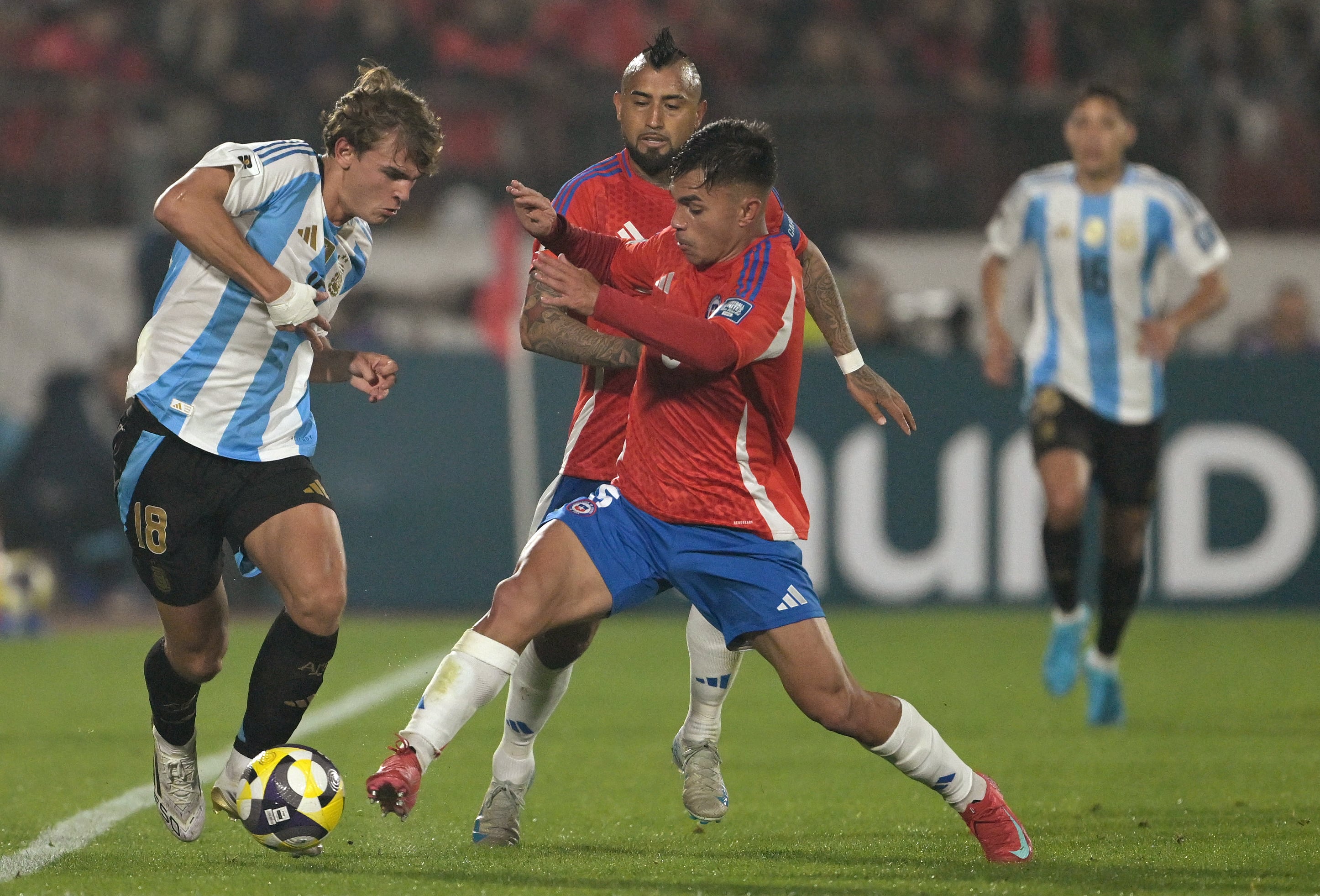 Nicolás Paz lleva la pelota ante dos adversarios