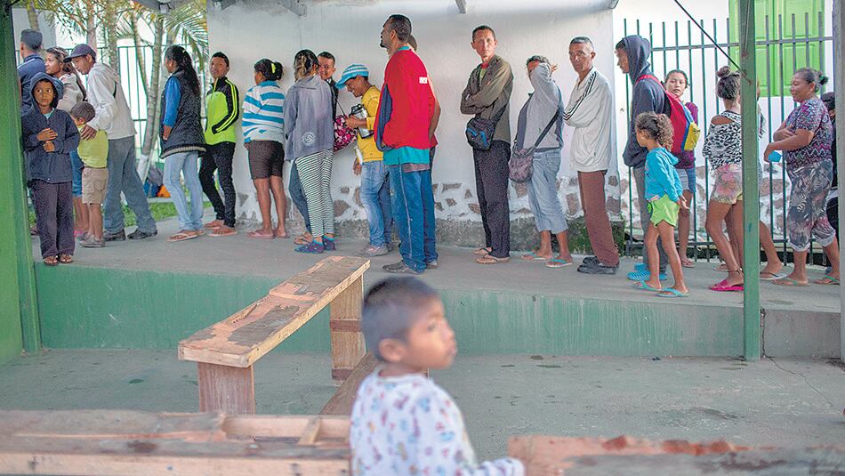 Inmigrantes venezolanos hacen fila para desayunar en una parroquia en Pacaraima, estado de Roraima, Brasil.