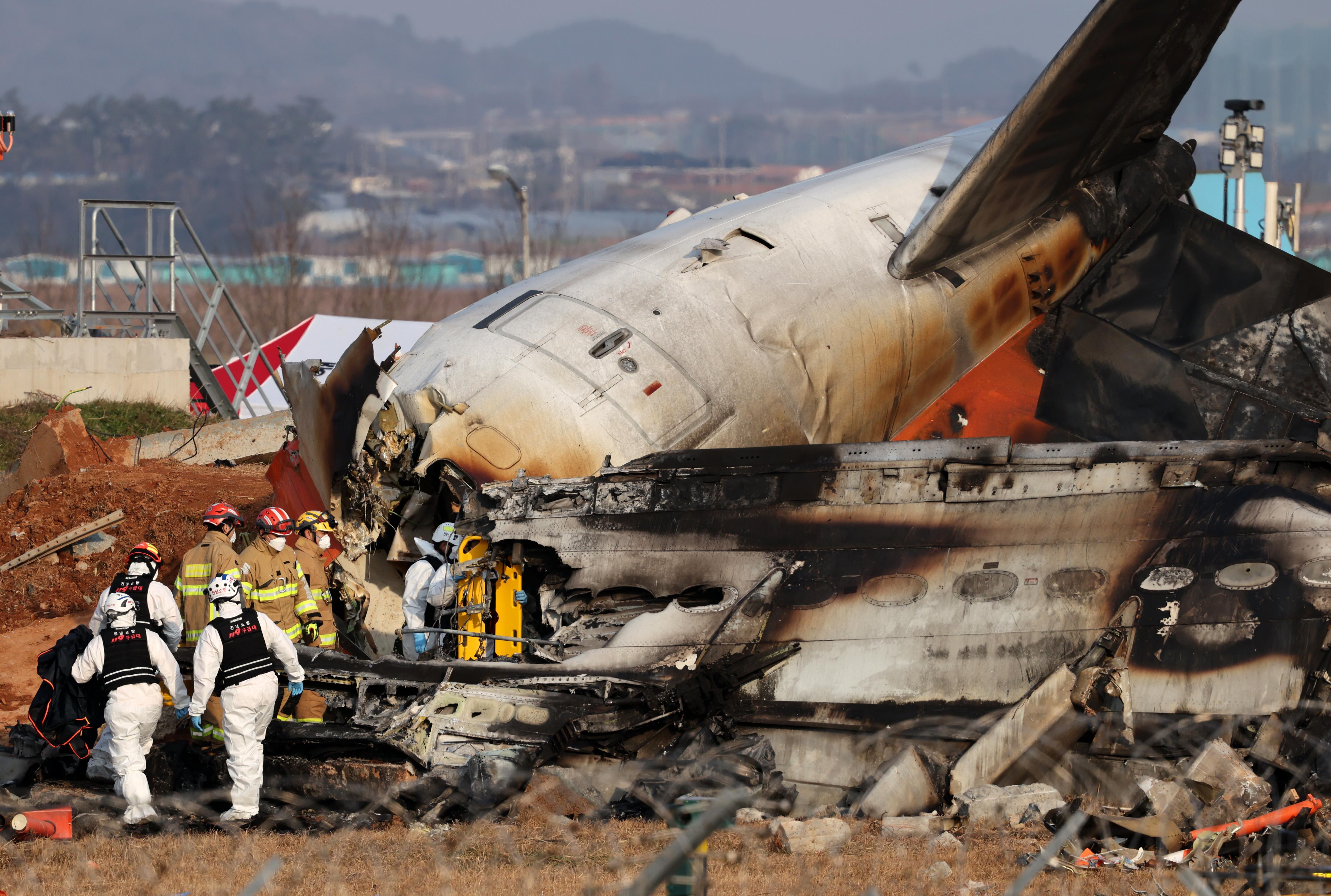 Los bomberos trabajan en los restos del avión Jeju Air en el Aeropuerto Internacional de Muan