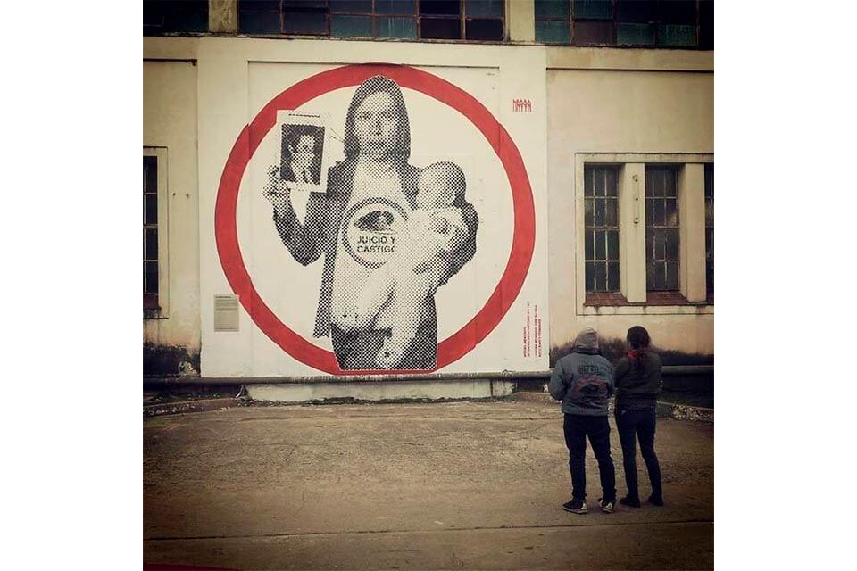 En una pared de la Esma: Lorena con su hija sosteniendo la foto de su padre.