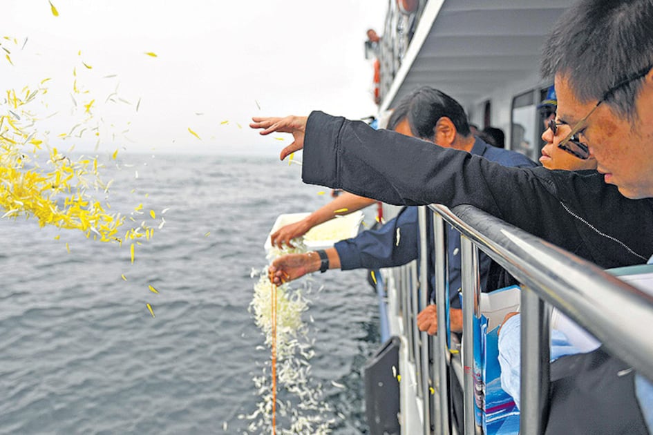 La viuda de Liu Xiabo (der.) tira pétalos de flores al mar durante la ceremonia.
