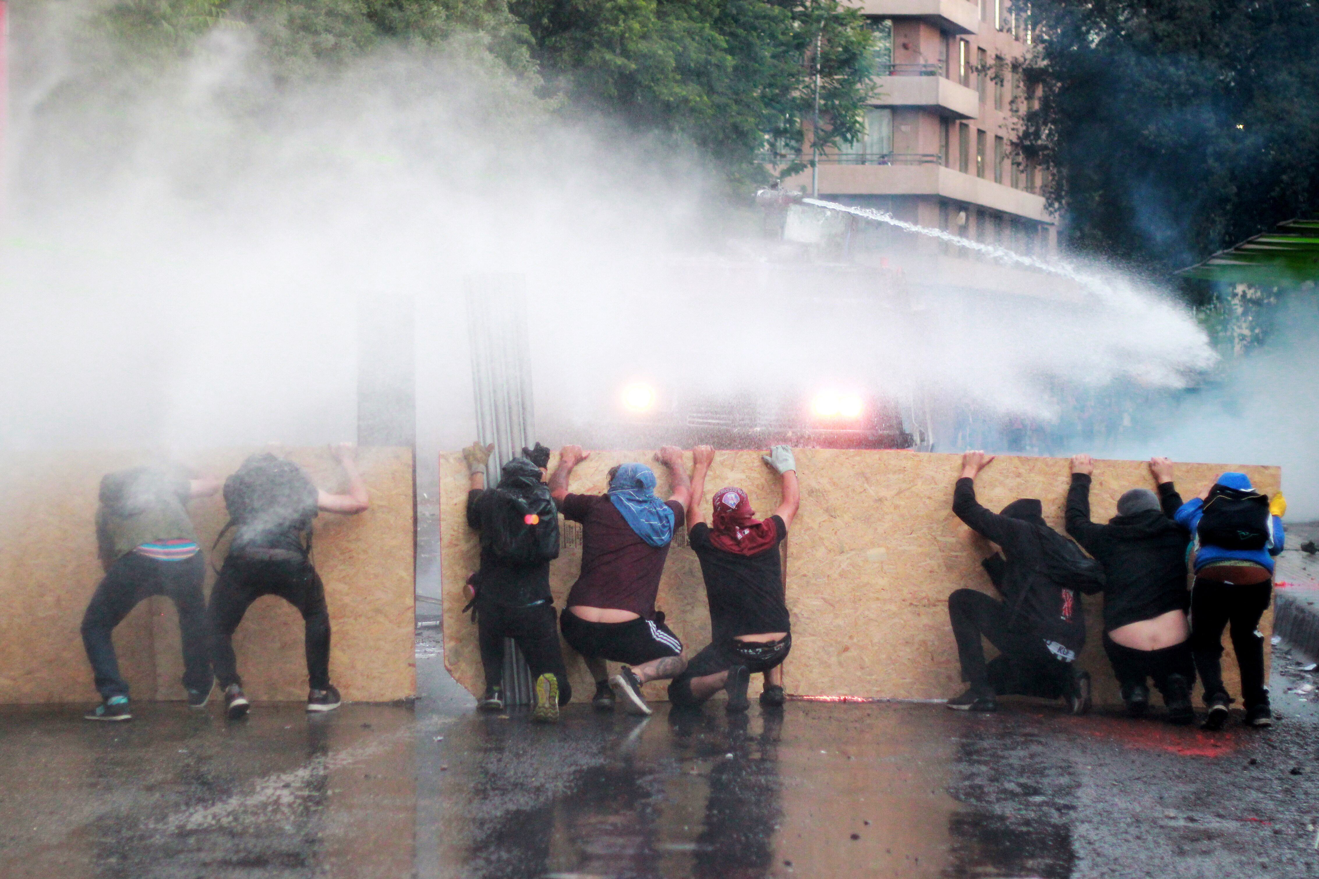 Resistiendo los chorros de los camiones hidrantes en las calles de Santiago.