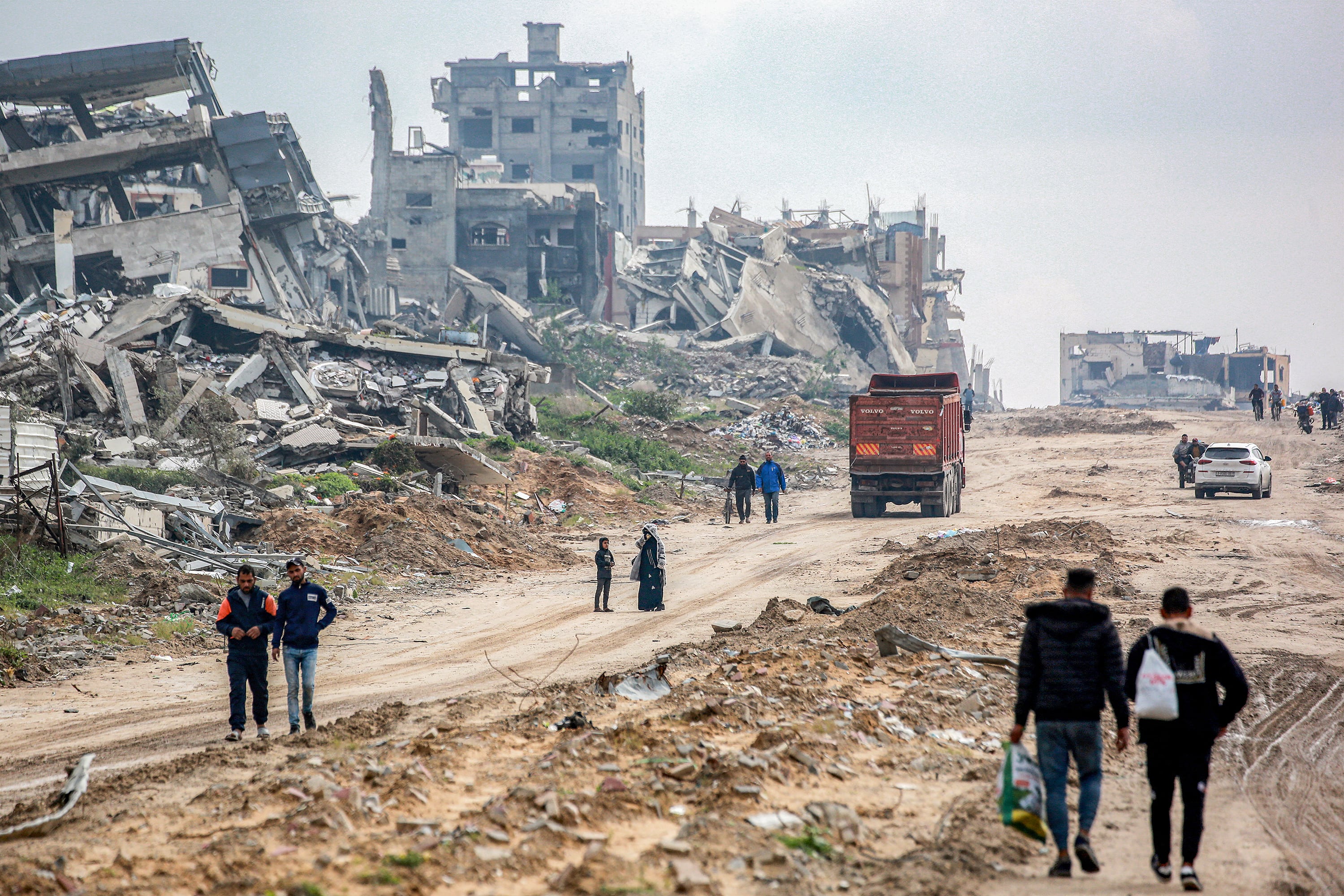 Varias personas caminan entre los edificios destruidos en Beit Lahia, al norte de la Franja