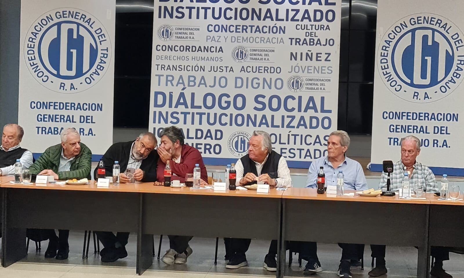 Gerardo Martínez cuchichea con Héctor Daer bajo la atenta mirada de Luis Barrionuevo.