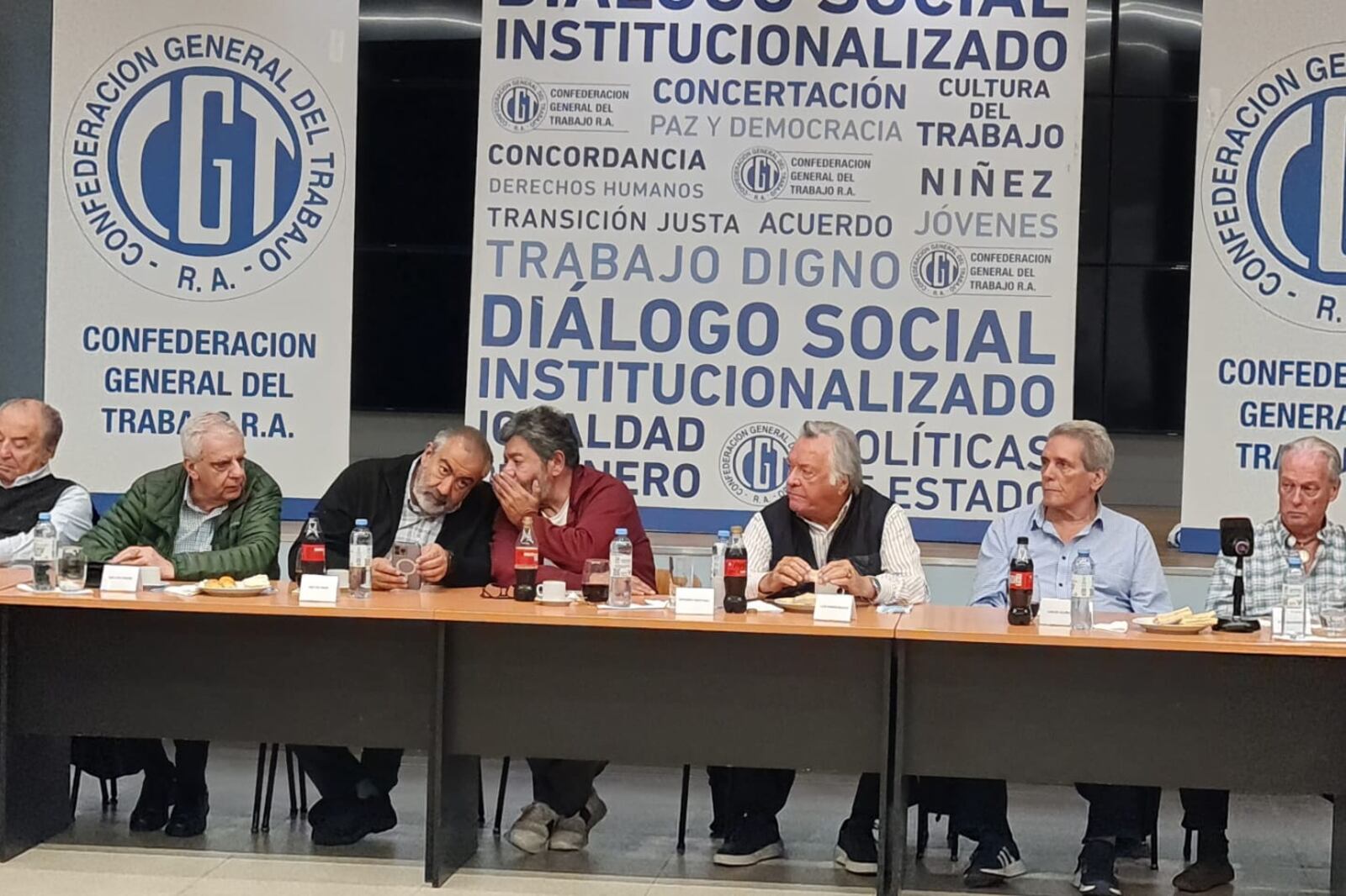 Gerardo Martínez cuchichea con Héctor Daer bajo la atenta mirada de Luis Barrionuevo.