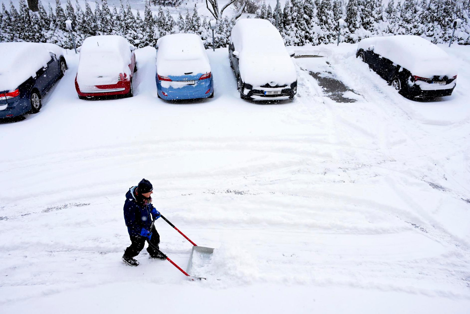 Tras un fuerte nevada, un hombre limpia el estacionamiento de un edificio residencial en Estocolmo, Suecia. 