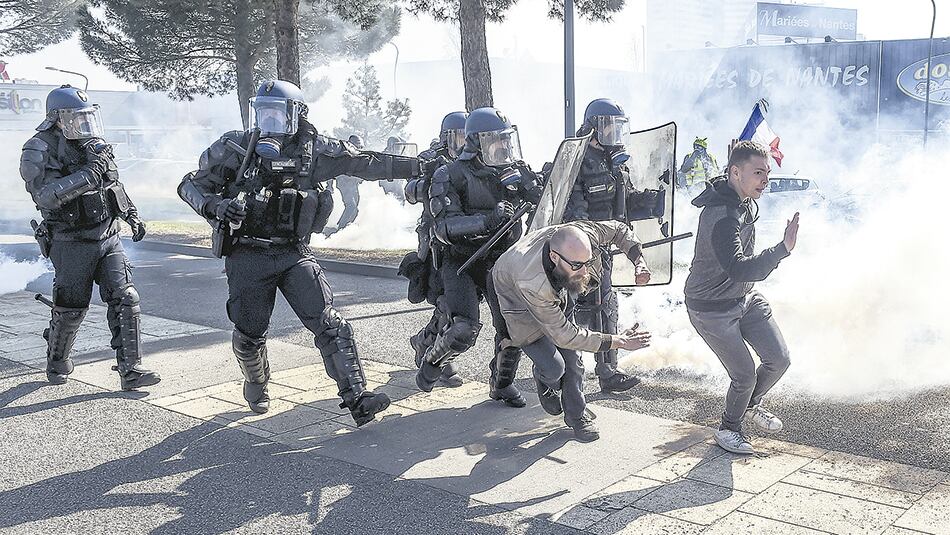 Chalecos amarillos levantan las manos y escapan de la policía en Saint-Herblain, cerca de Nantes.