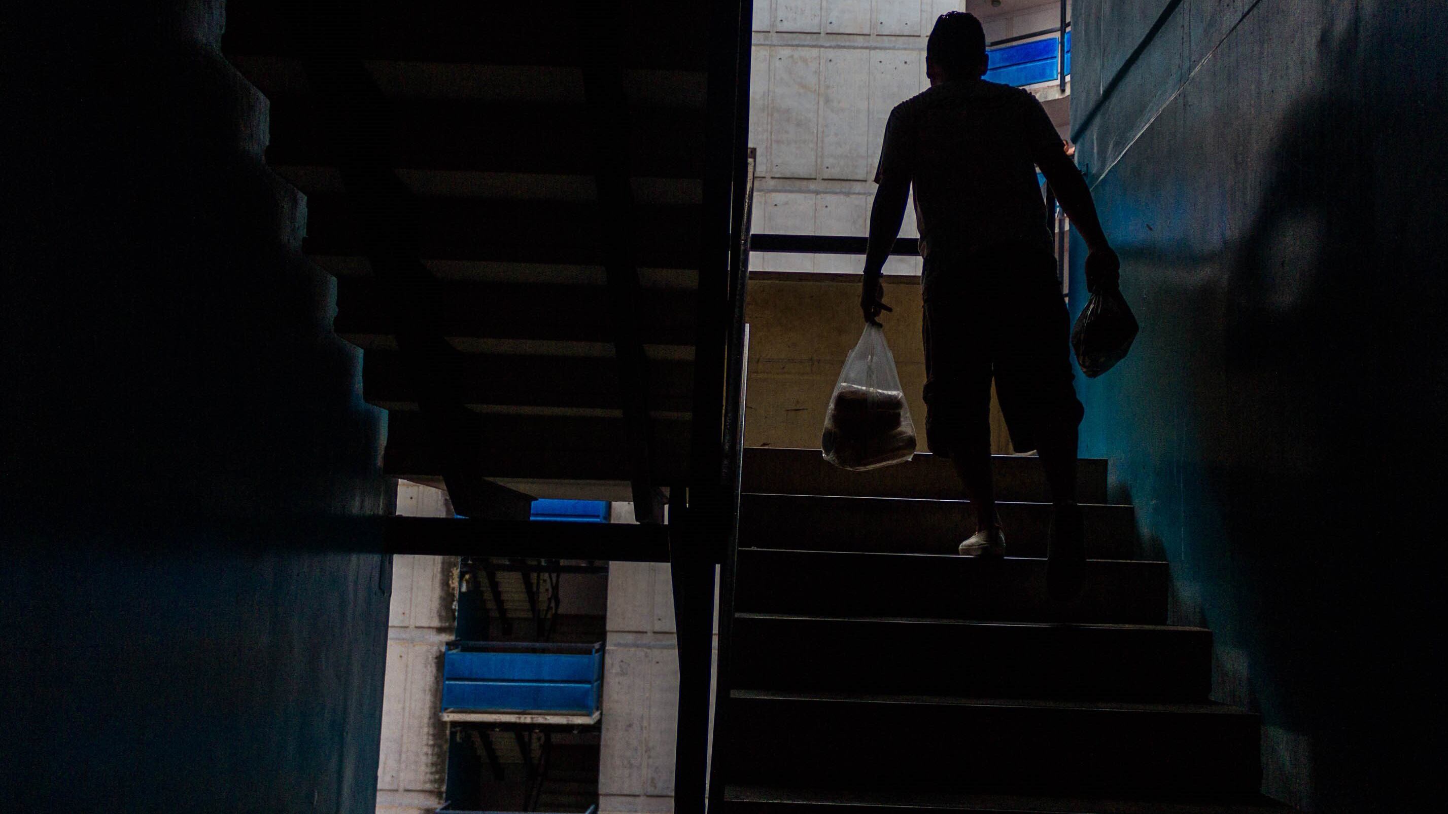 Un residente de Caracas regresa a su vivienda con una bolsa de compras en medio del apagón.