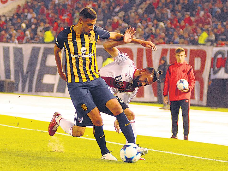 n Ariel Rojas, que no tuvo un buen desempeño, intenta ganar la pelota ante Damián Musto.