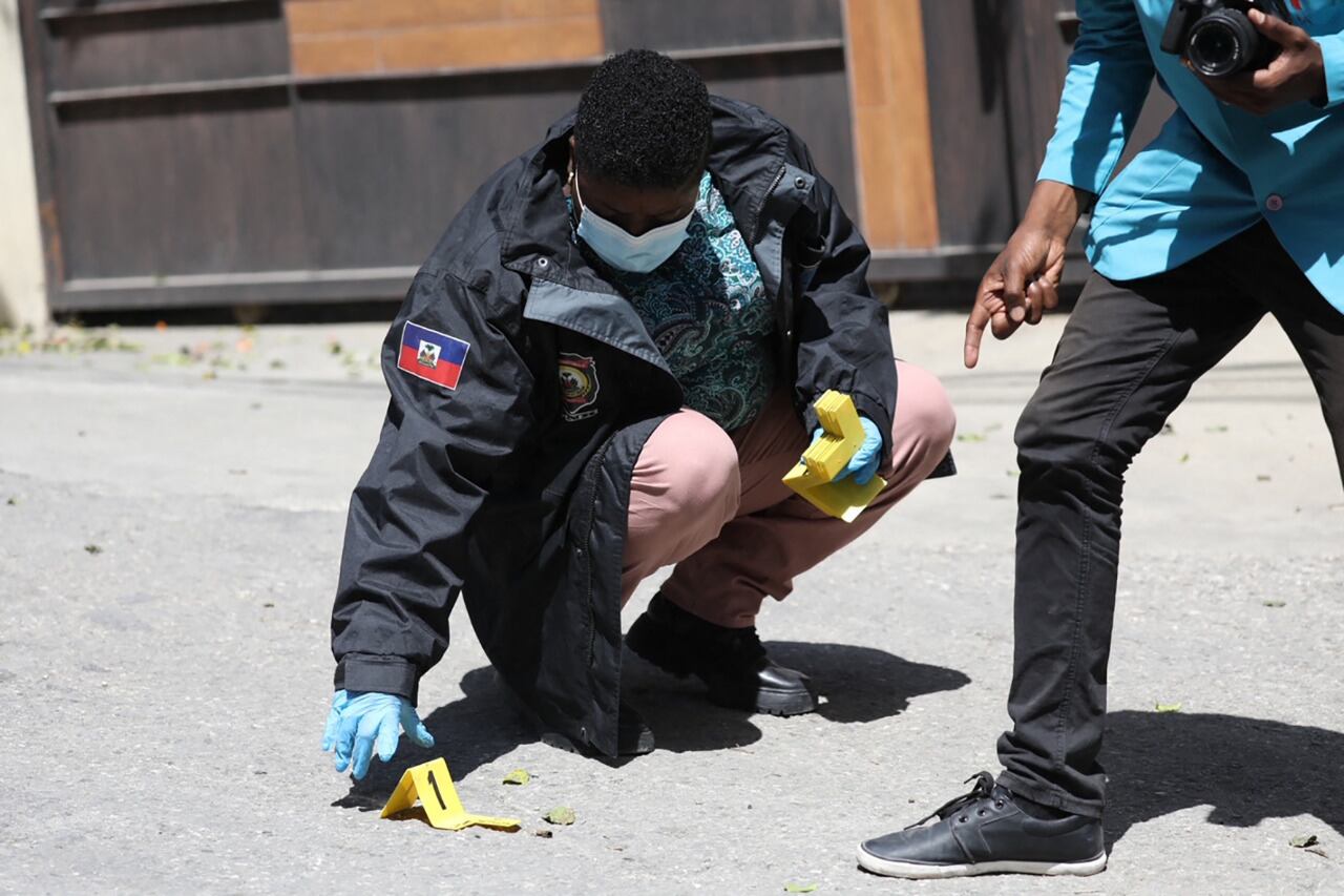 Miembros de la policía forense marcan pruebas frenta al palacio presidencial en Puerto Príncipe.