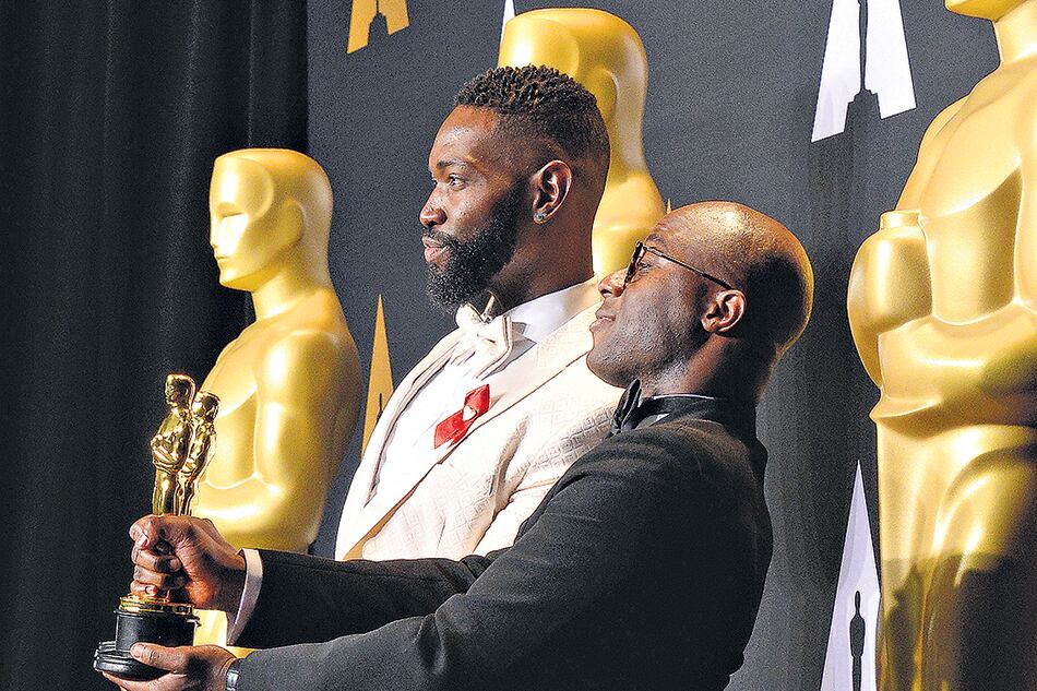Tarell Alvin McCraney y Barry Jenkins festejan el Oscar al mejor guión adaptado.