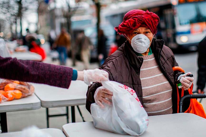 Una mujer desempleada recibe de manos de una voluntaria una bolsa de comida en Nueva York, el pasado 28 de marzo.