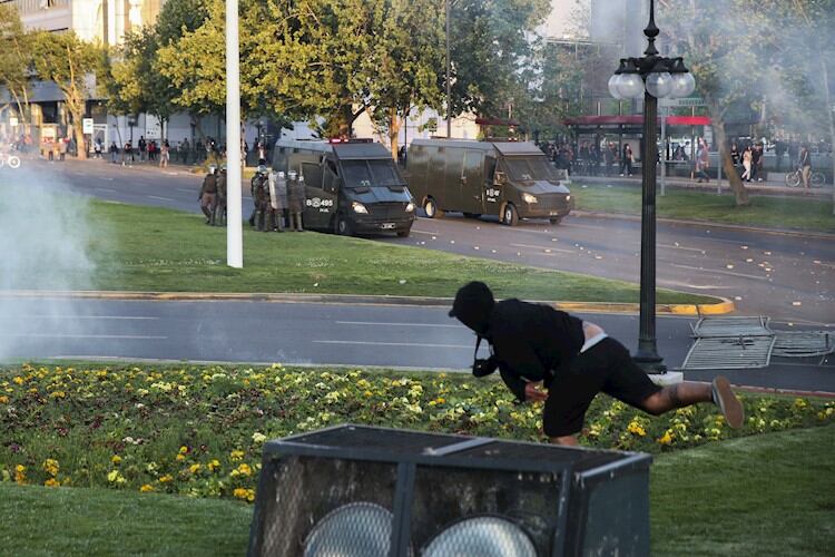 Un manifestante enfrenta a los carabineros en las calles de Santiago.