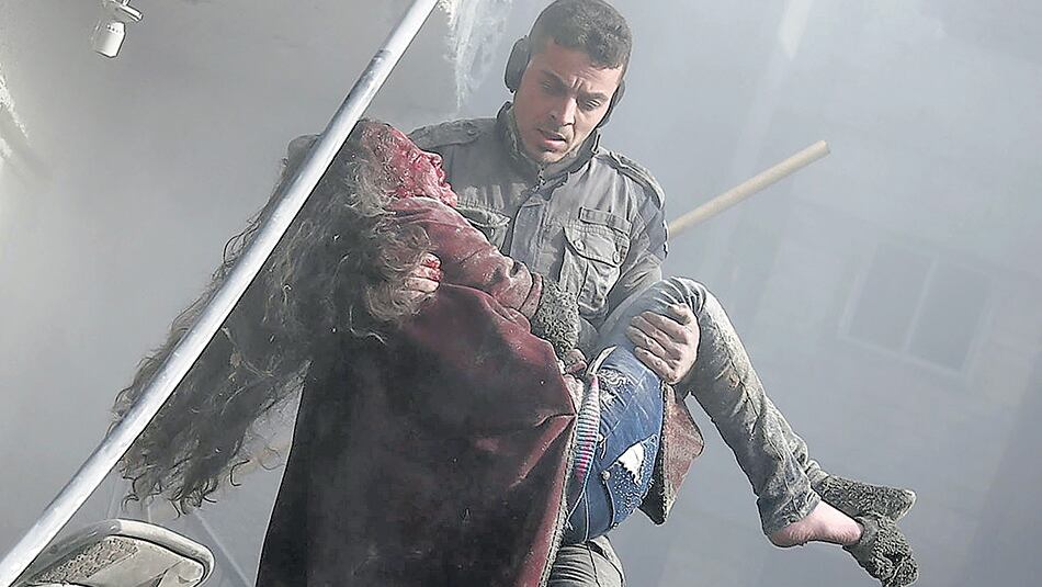 Un voluntario de la defensa civil levanta a una niña herida tras un bombardeo en Guta.