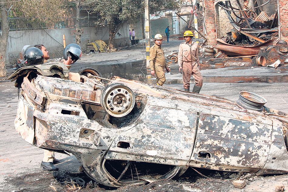 Bomberos apagan un auto incendiado en nueva Delhi en medio de los enfrentamientos.