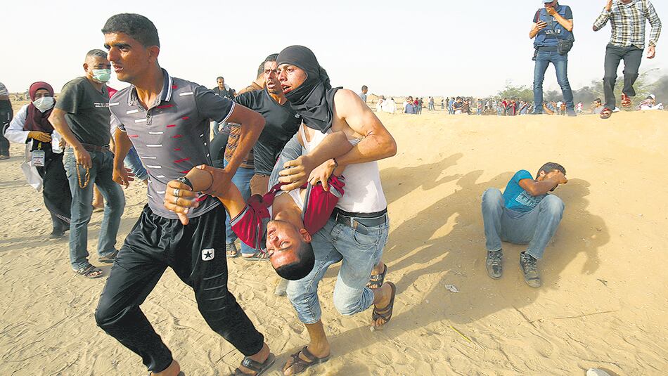 Manifestantes palestinos cargan con un herido durante una protesta en el límite de la Franja de Gaza.