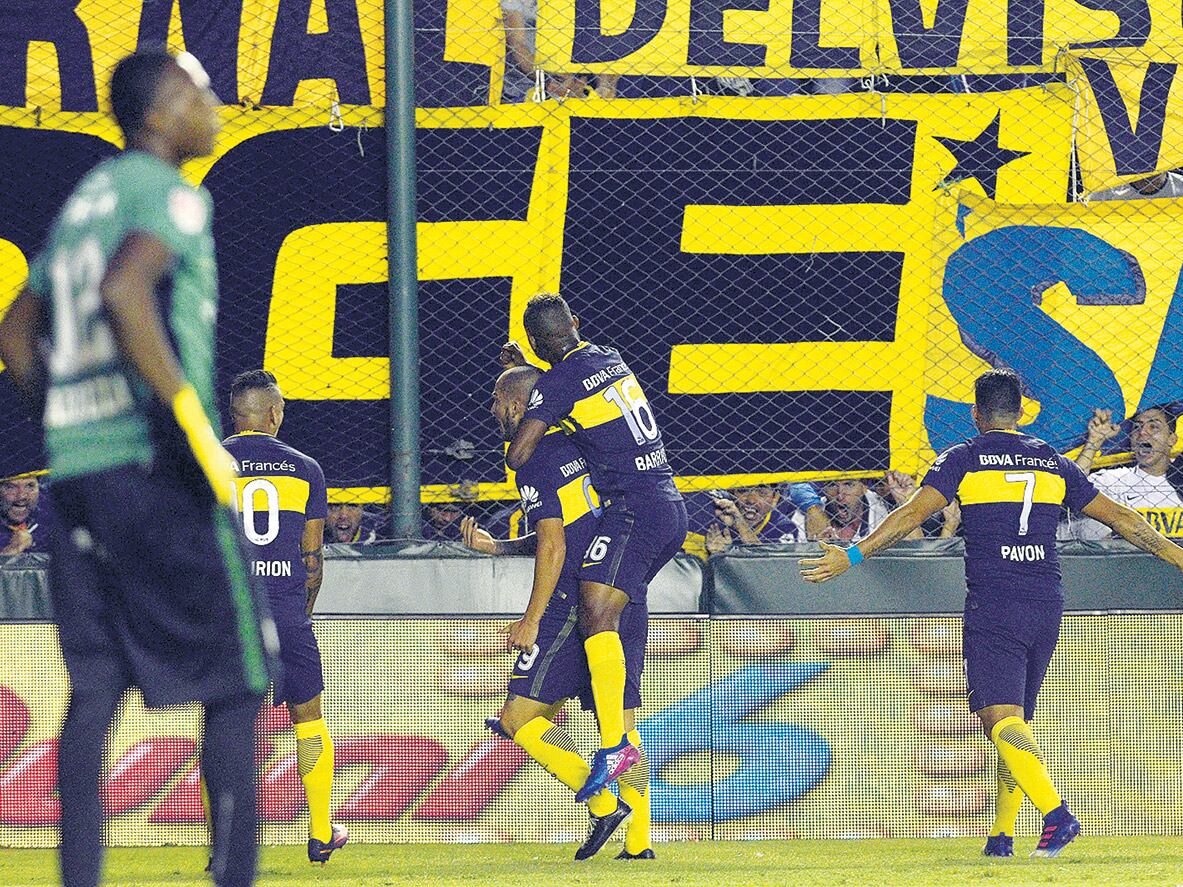 El asistidor Fabra trepa sobre la humanidad del goleador Benedetto para festejar el primero de Boca en Banfield.