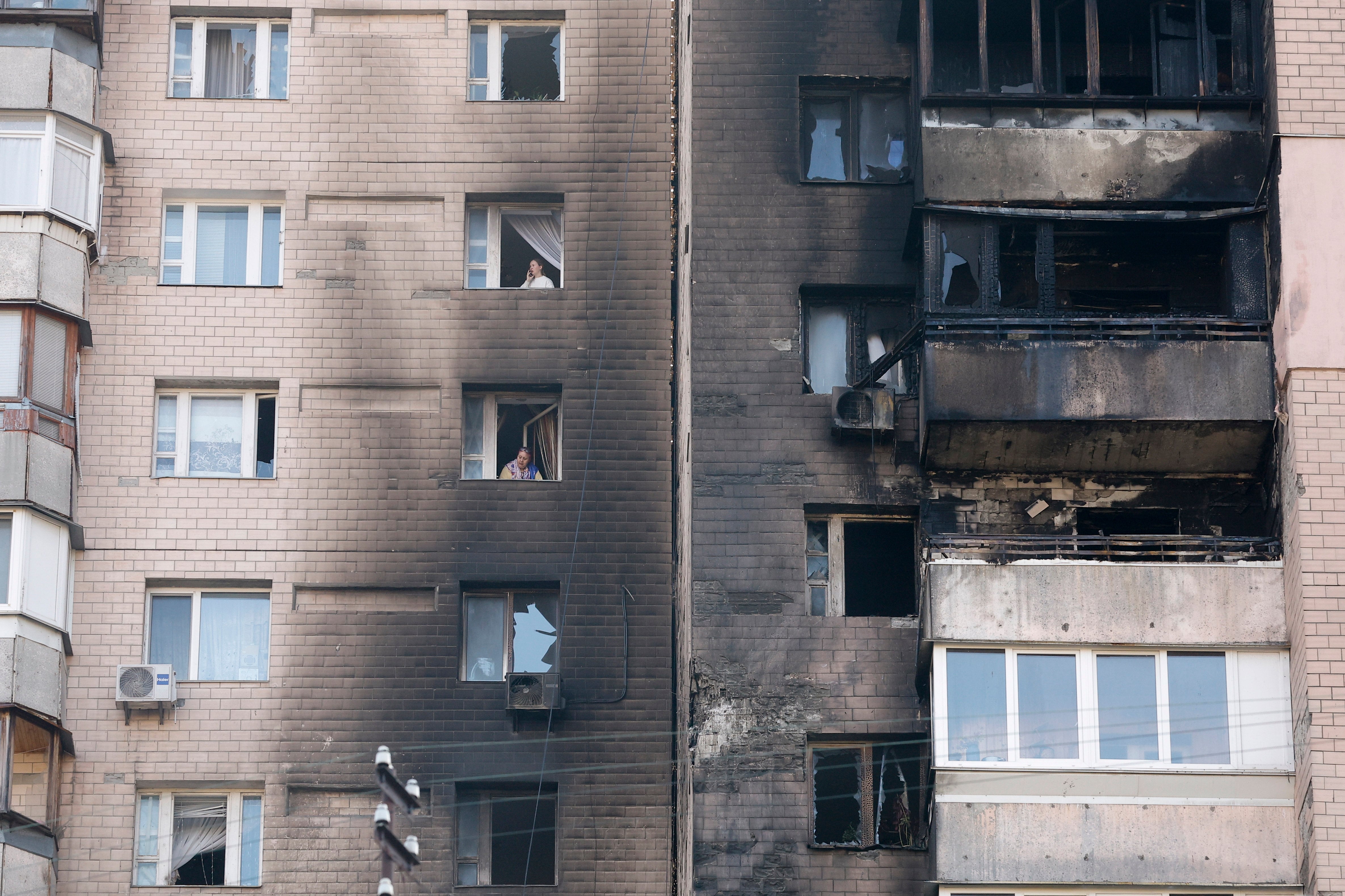 Unvecino mira por la ventana un edificio de Kiev bombardeado por Rusia.