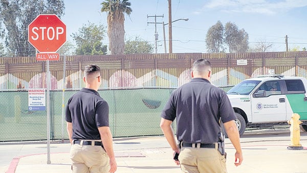 Agentes en Calexico, California, patrullan cerca de una reja que marca el límite con México.